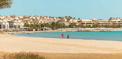 Strand med byggnader och palmer i bakgrunden. (AI-genererad text)