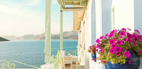 Terrass med utsikt över havet och berg, blomhinkar i förgrunden. (AI-genererad text)