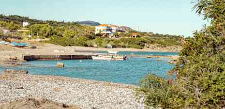 En strand med båtar och hus i bakgrunden. (AI-genererad text)