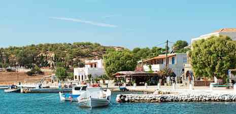 Hamnmiljö med småbåtar, hus och träd vid kustlinjen. (AI-genererad text)