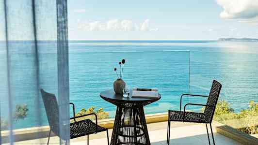 Balkong med havsutsikt, bord med vas och två stolar. (AI-genererad text)