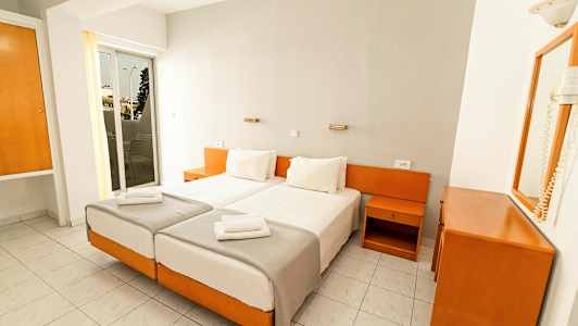 Två enkelsängar med vita sängkläder i ett hotellrum med vitt och träinredning. (AI-genererad text)