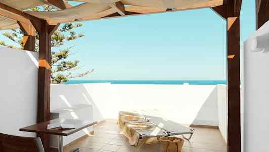 Terrass med havsutsikt, solstolar och bord under överbyggnad. (AI-genererad text)