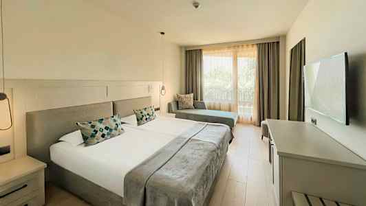 Ett hotellrum med två enkelsängar, en soffa och en TV. (AI-genererad text)