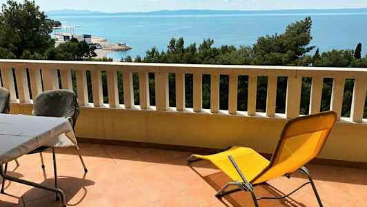 Balkong med bord, stolar och solstol samt utsikt över havet. (AI-genererad text)