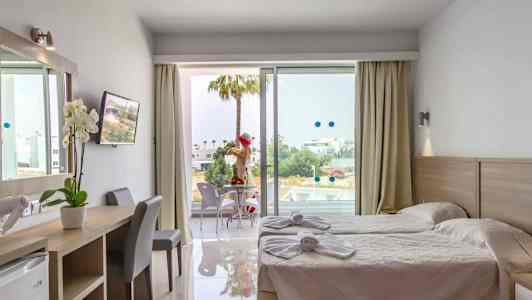 Hotellrum med två enkelsängar, skrivbord och balkong med sittplatser. (AI-genererad text)