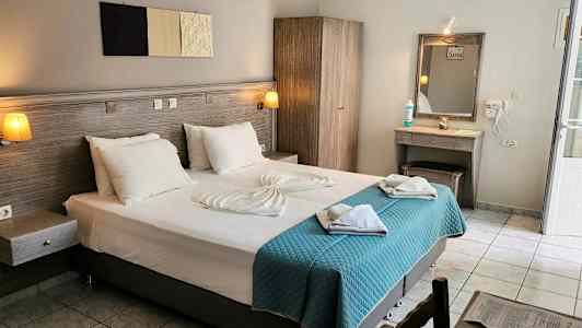 Hotellrum med en dubbelsäng, garderob, sminkbord, och ljusa textilier. (AI-genererad text)