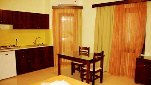 Ett rum med ett kök, bord och två stolar samt gardiner vid fönstren. (AI-genererad text)