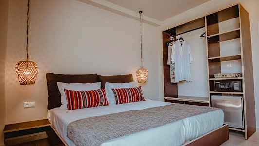 Sovrum med dubbelsäng, röda dekorativa kuddar och öppen garderob. (AI-genererad text)