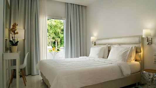 Ljust och modernt inrett hotellrum med en stor säng och fönster med utsikt. (AI-genererad text)