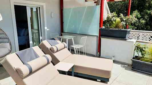 Terrass med två solstolar och ett bord med två stolar under en pergola. (AI-genererad text)