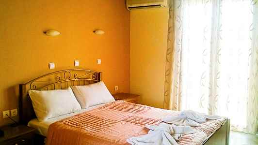 Ett sovrum med en dubbelsäng, orange sängkläder och två handdukar dekorerade på sängen. (AI-genererad text)