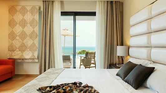 Hotellrum med en säng och havsutsikt från en möblerad terrass. (AI-genererad text)