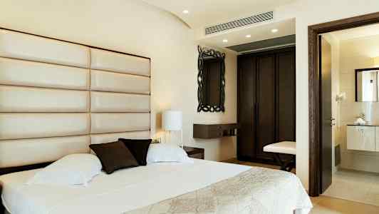 Hotellrum med en stor säng, ljus lampett, och ett badrum i bakgrunden. (AI-genererad text)