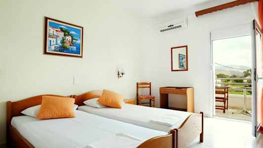 Hotellrum med två enkelsängar, en skrivbord med stol och balkong med utsikt. (AI-genererad text)