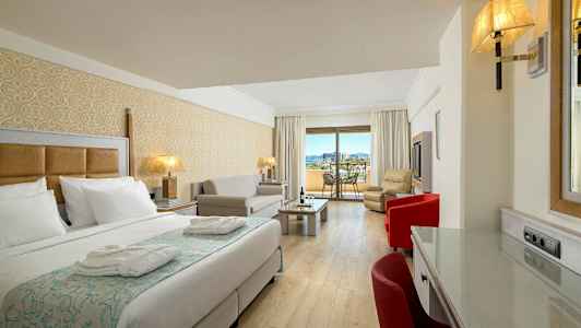 Ett hotellrum med en säng, sittgrupp och en balkong med utsikt. (AI-genererad text)