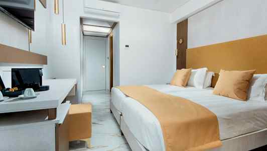 Ett modernt hotellrum med en stor säng, marmorgolv och en arbetsyta med kaffemaskin. (AI-genererad text)