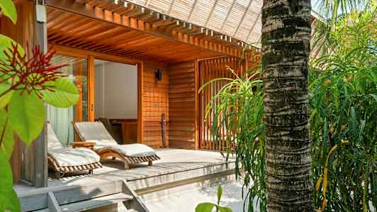 Träterrass med solstolar och omgivande grönska vid en träbyggnad. (AI-genererad text)