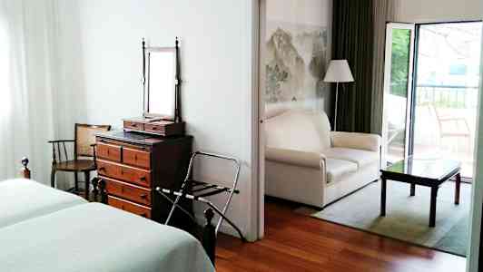 Ett hotellrum med två sängar, en byrå med spegel och en öppen sittgrupp med soffa och bord. (AI-genererad text)