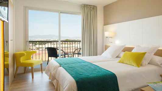 Ett hotellrum med två sängar, en stol och en balkong med utsikt. (AI-genererad text)