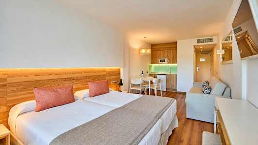 Inredning av ett hotellrum med dubbelsäng, köksdel och sittplats. (AI-genererad text)