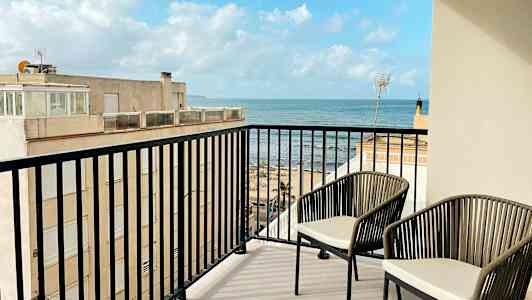 En balkong med två stolar och vy över havet. (AI-genererad text)