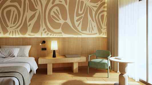 Bild av ett modernt hotellrum med dekorativ konst på väggen. Det finns en säng till vänster, ett nattduksbord med en lampa, en grön stol och ett runt bord nära ett stort fönster. (AI-genererad text)