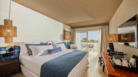 Hotellrum med stor säng, modern dekor och balkong med utsikt. (AI-genererad text)