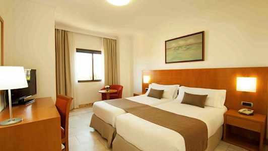 Ett hotellrum med två enkelsängar och träpanel på väggen. (AI-genererad text)