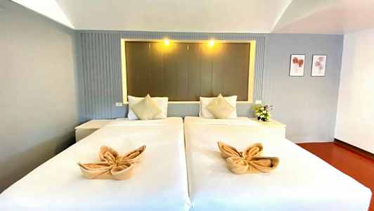 Två enkelsängar med dekorerade handdukar och kuddar, belägna i ett stilfullt rum. (AI-genererad text)