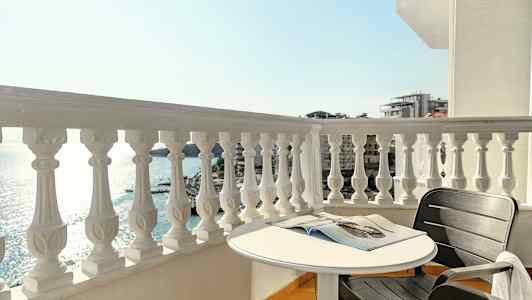 En balkong med utsikt över havet, ett runt bord och en svart stol. (AI-genererad text)
