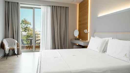 Ett modernt hotellrum med en stor säng, ett skrivbord, en stol och en balkong med möbler. (AI-genererad text)