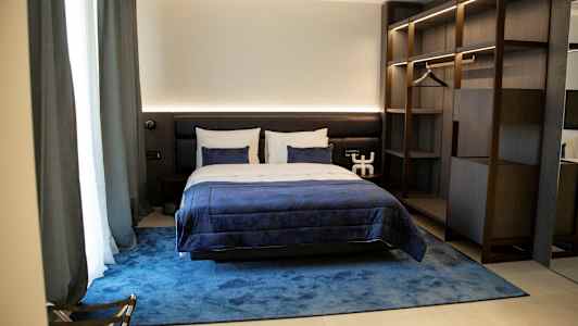 Ett bekvämt hotellrum med en dubbelsäng, blå sängkläder och en snygg inredning. (AI-genererad text)