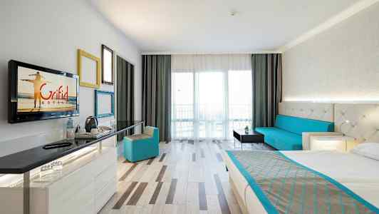 Ett hotellrum med en säng, en sittgrupp, ett skrivbord och en balkong. (AI-genererad text)