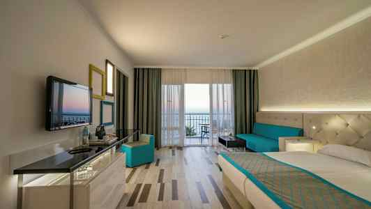 Interiör av ett hotellrum med en säng, soffa och utsikt mot en balkong. (AI-genererad text)