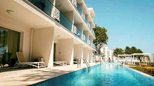 Hotellbyggnad med balkonger och poolområde. (AI-genererad text)