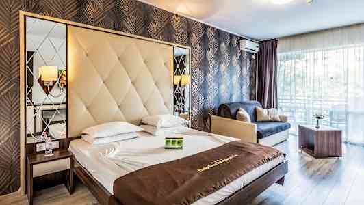 Ett hotellrum med en dubbelksäng, en soffa och ett bord. Rummet har en modern inredning med snygga mönstrade väggar. (AI-genererad text)