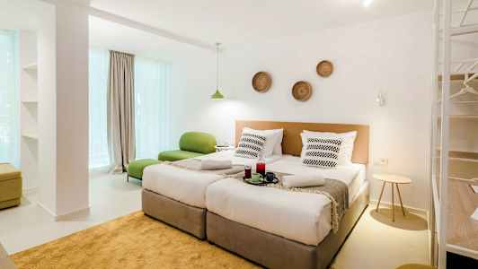 Ett modernt hotellrum med två enkelsängar, grön sittmöbel och dekorationer på väggen. (AI-genererad text)