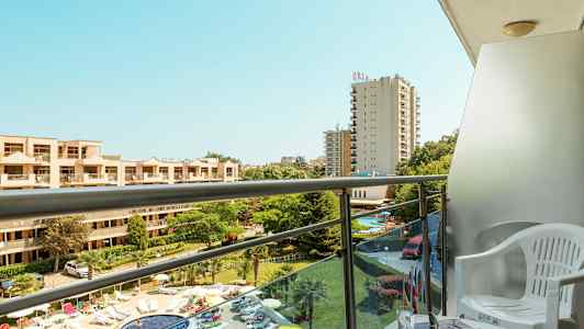 Lägenhetsbalkong med utsikt över poolområdet och hotellbyggnader. (AI-genererad text)