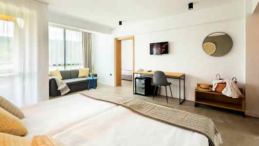 Modernt hotellrum med dubbelsäng, soffa och skrivbord. (AI-genererad text)