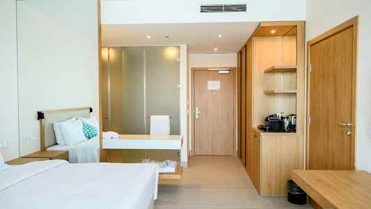 Ett hotellrum med en säng, skrivbord och en liten köksenhet. (AI-genererad text)