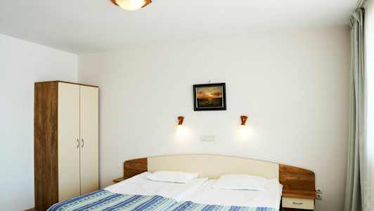 Ett hotellrum med en dubbelsäng, nattduksbord och garderob. (AI-genererad text)