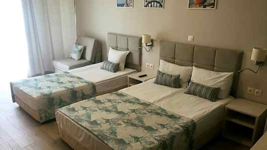 Dubbelrum med två sängar, en soffa och ljus inredning. (AI-genererad text)