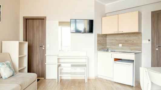 En liten kök och vardagsrumsdel med soffa, skåp, tv och köksutrustning. (AI-genererad text)