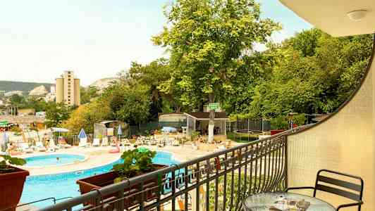 Utsikt från en altan mot en utomhuspool, solstolar och grönska. (AI-genererad text)