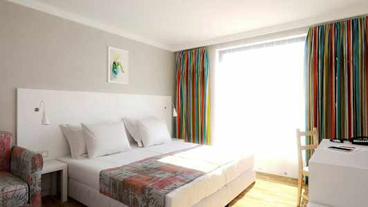 Ett hotellrum med en säng, ett skrivbord och färgstarka gardiner. (AI-genererad text)