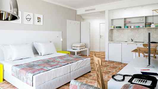 Modernt hotellrum med dubbelsäng, kök och arbetsbord. (AI-genererad text)