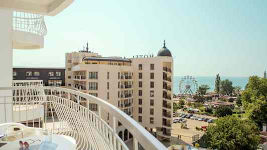 Utsikt från en balkong över ett hotellområde med en pariserhjul och havet i bakgrunden. (AI-genererad text)