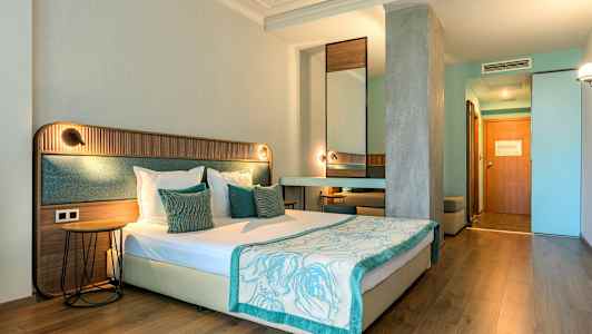 Ett hotellrum med en dubbelsäng, trä- och tygelement, ljusa väggar och träinredning. (AI-genererad text)