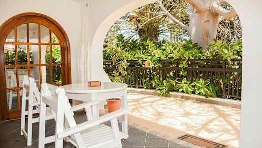 En uteplats med vita trämöbler och grönskande växter. (AI-genererad text)